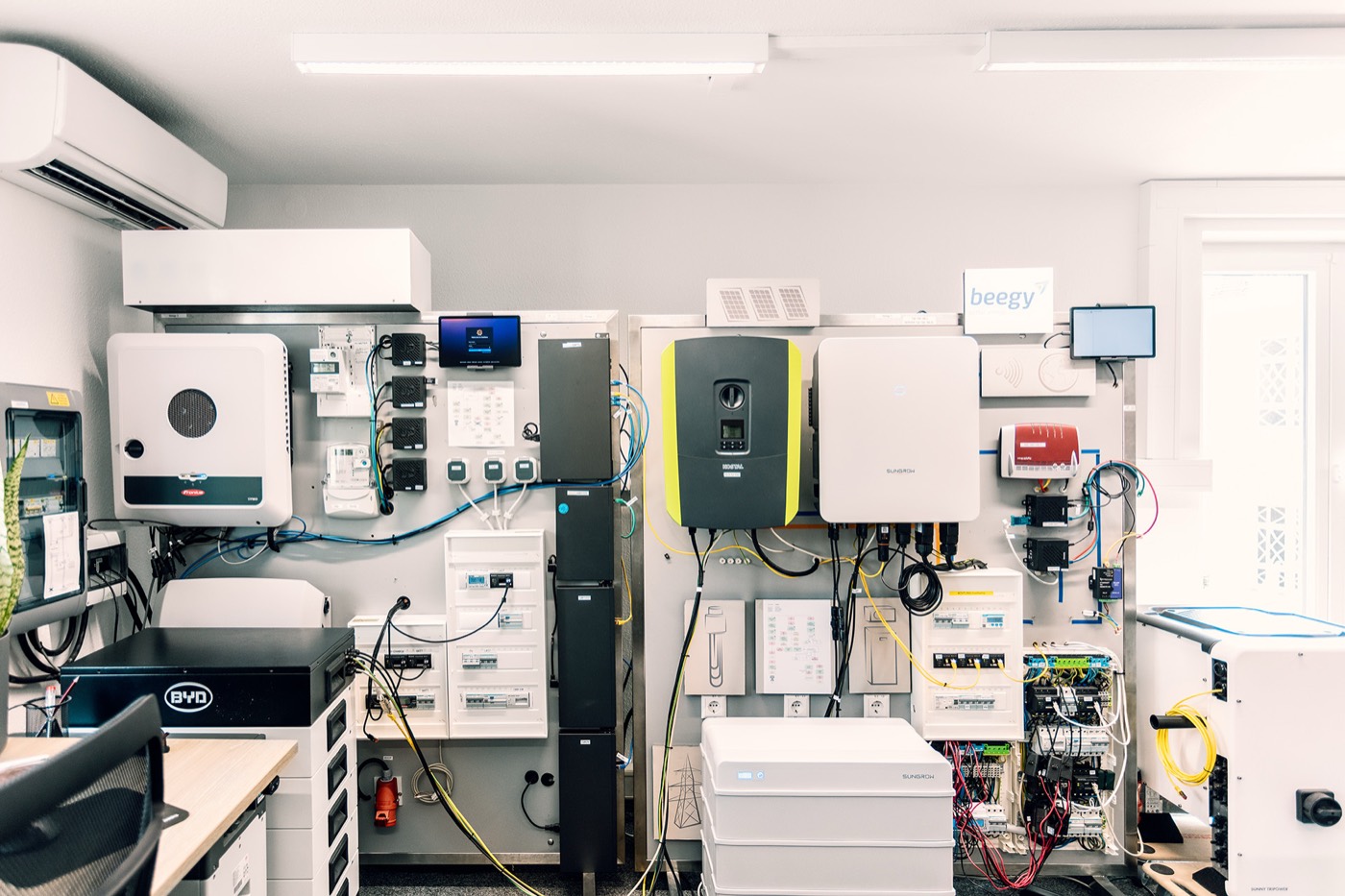 Overview of the EnQS Testlab wall with PV and battery inverters, a battery storage unit and switchgear